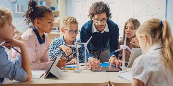 Teacher showing a group of young children students in classroom a physics experiment with miniature windmills