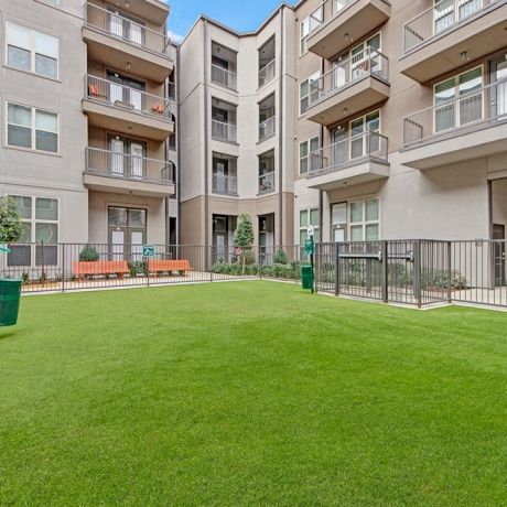 The Civic At Frisco Square apartment exterior featuring large green dog park with fence