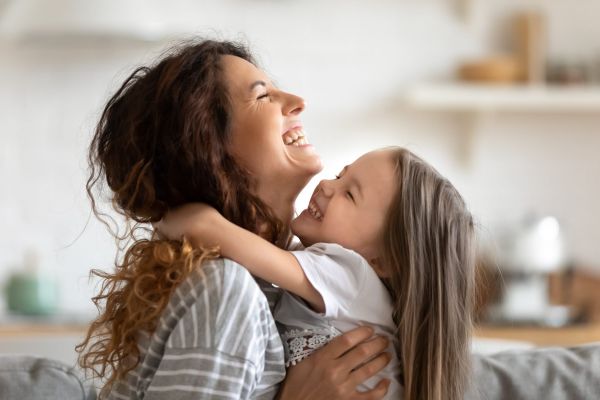 Close up side view overjoyed smiling young mother and daughter hugging and laughing