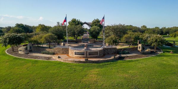 Frisco Commons Park in Frisco, TX with large green lawn and flags